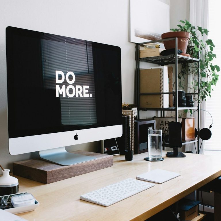 Texte erstellen lassen inkl. Suchmaschinenoptimierung Ein moderner Schreibtisch mit einem iMac und der Aufschrift "DO MORE."